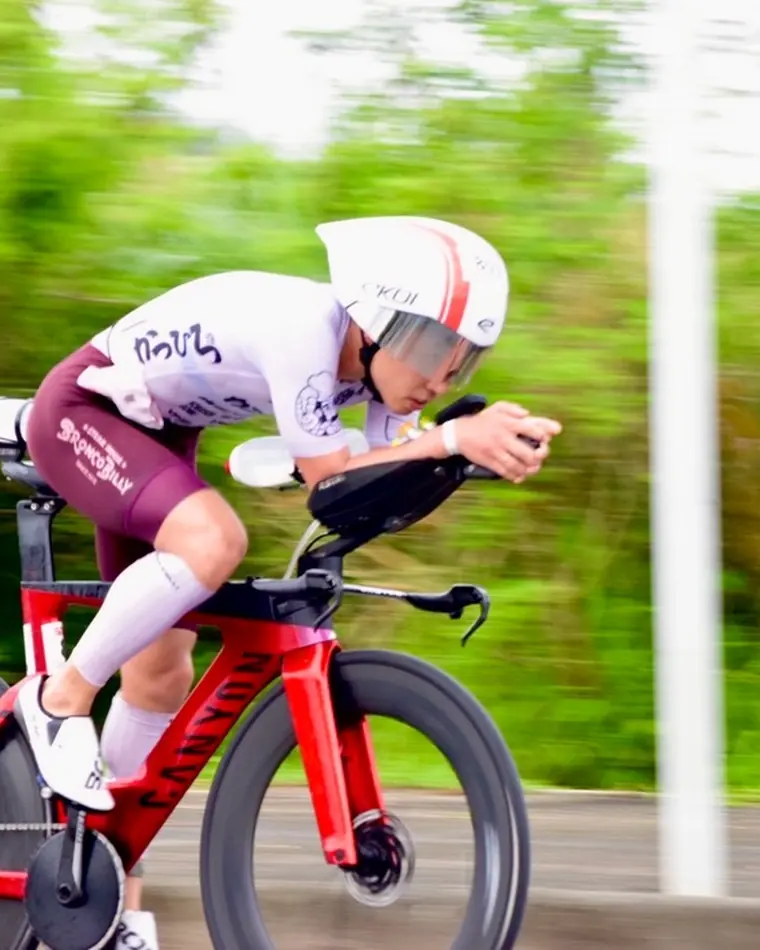 Triathlete in an aero position on a red time-trial bike