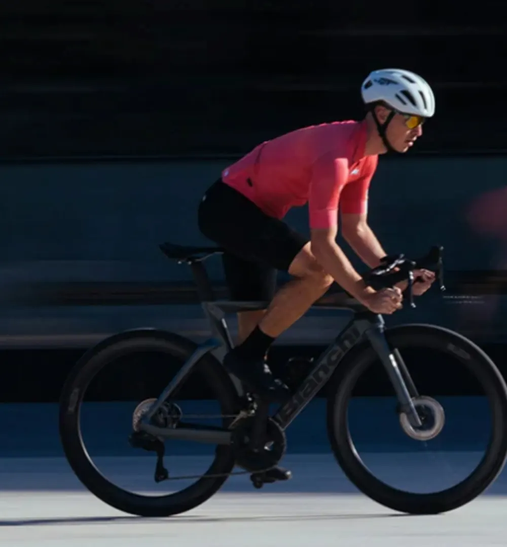Cyclist in a red jersey riding a black road bike with deep carbon wheels
